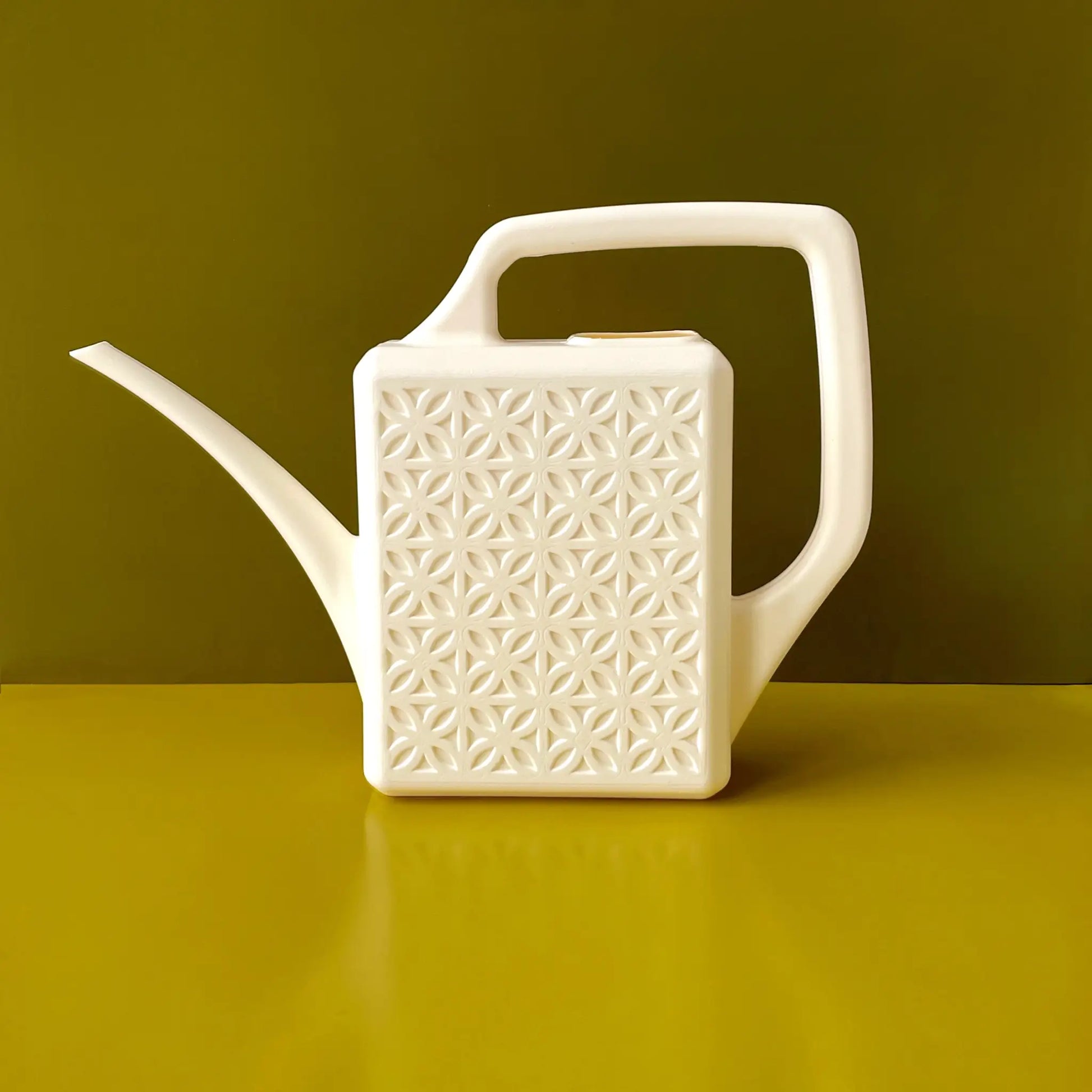 Ivory Breeze Block watering can sitting on yellow table, decorative and functional